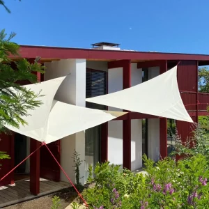 Voiles triangulaires claires installées devant une maison